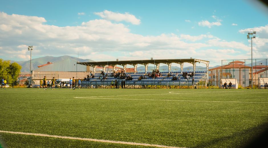 A grass soccer field with players and spectators in Malatya, Türkiye.