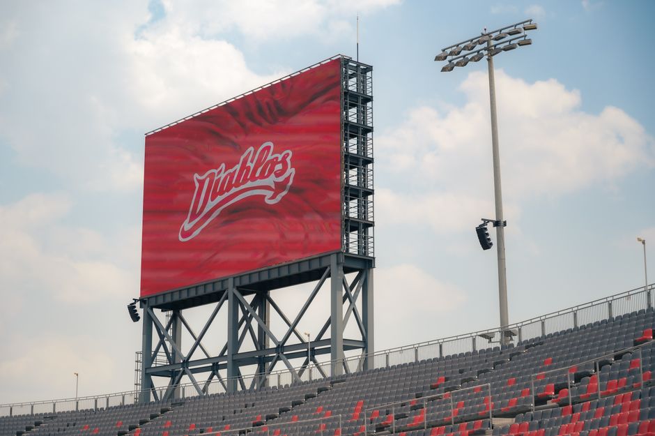 Large jumbotron showcasing logo in an outdoor stadium setting with bleachers and clear sky.